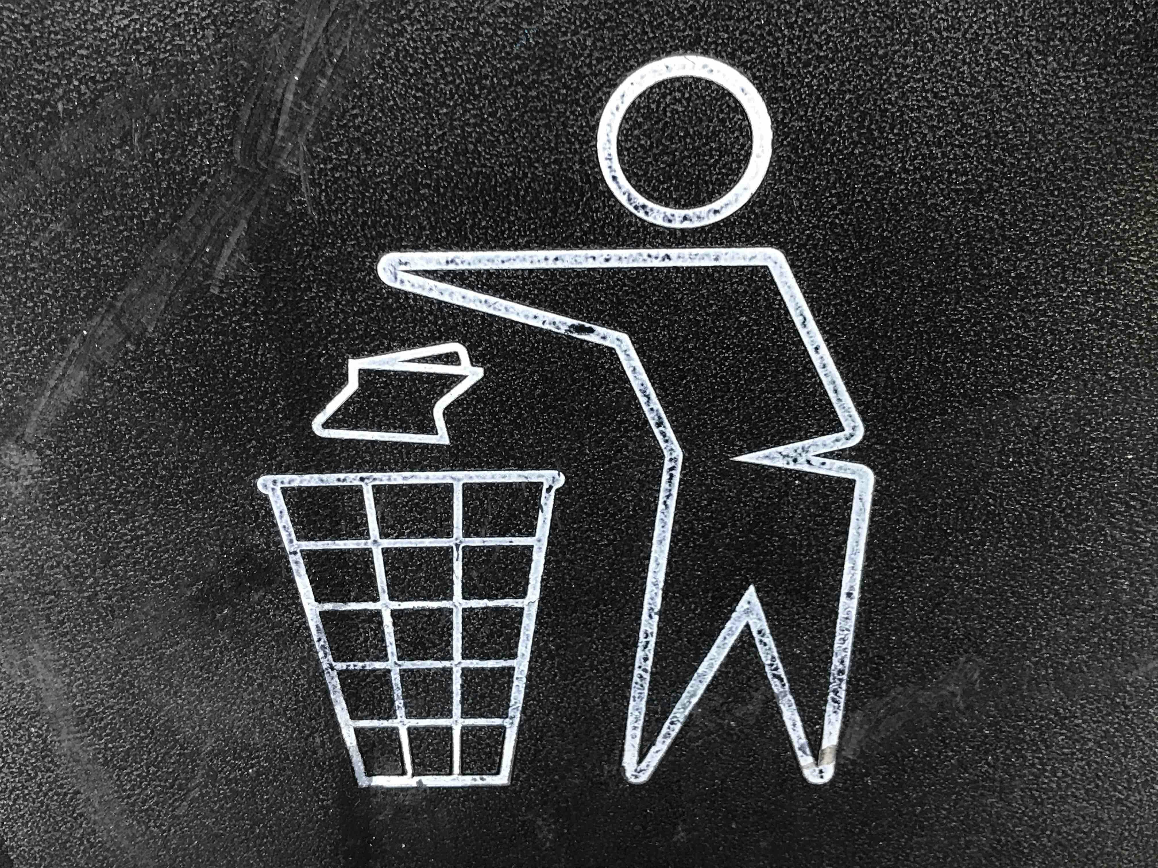 picture of stick figure throwing balled up trash ino a garbage can.
