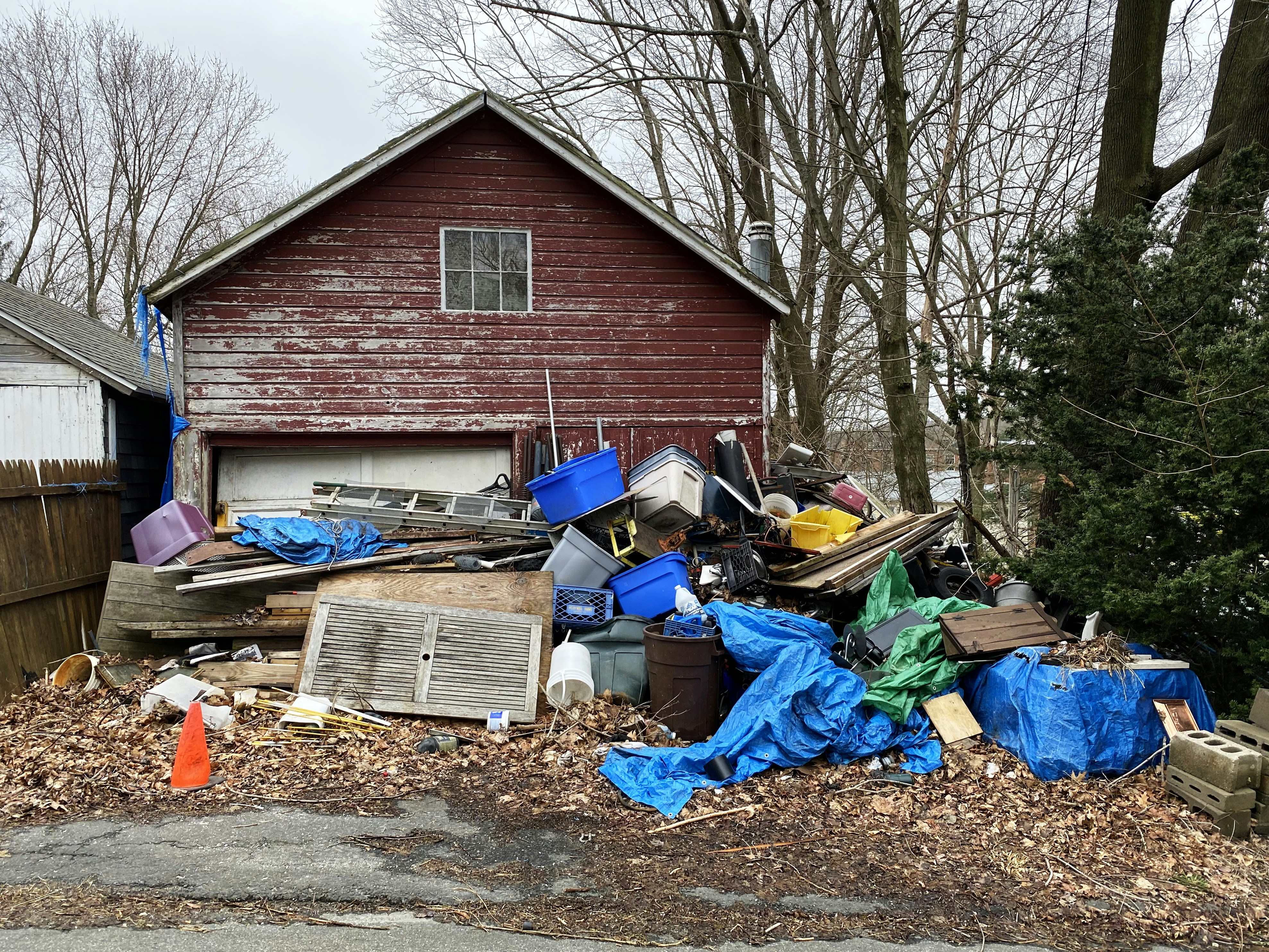 picture of large pile of junk outside of a home on driveway, extenending to the sidewalk.